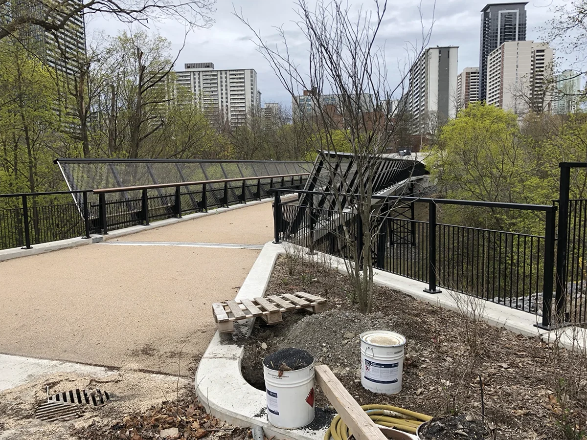 Bridge across ravine wiht trees and apartment buildings in background